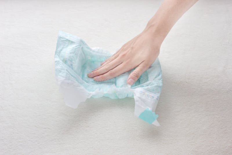 La mano della ragazza tocca la capacità di assorbimento dell'umidità di un pannolino del bambino, primo piano immagini stock libere da diritti La mano della ragazza tocca la capacità di assorbimento dell'umidità di un pannolino del bambino, primo piano immagini stock libere da diritti