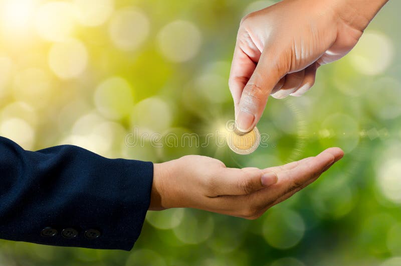 La mano envía la moneda que el fondo verde del bokeh da el dinero fotos de archivo La mano envía la moneda que el fondo verde del bokeh da el dinero fotos de archivo