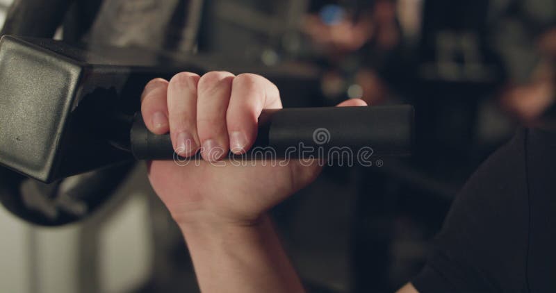 La mano estrecha del macho captura la manija del simulador para bombear triceps almacen de metraje de vídeo