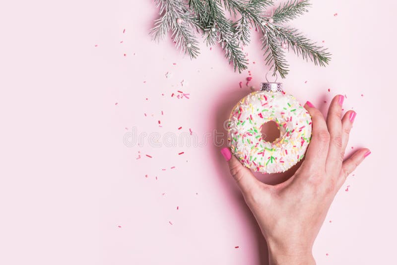 La mano femminile appende le decorazioni di Natale fatte di ciambella su sfondo rosa Concetto creativo di Natale fotografia stock La mano femminile appende le decorazioni di Natale fatte di ciambella su sfondo rosa Concetto creativo di Natale fotografia stock