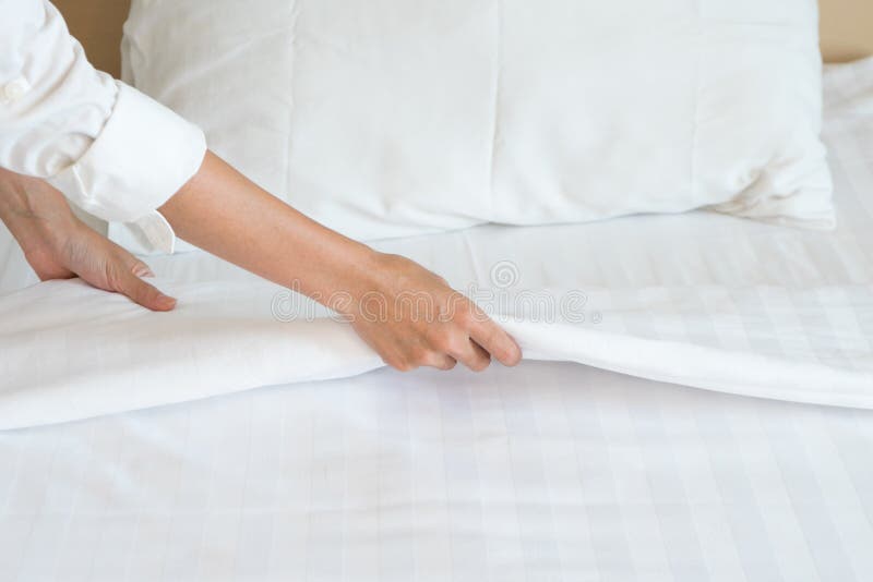 La mano femminile ha installato il lenzuolo bianco nell'hotel della sala fotografia stock libera da diritti La mano femminile ha installato il lenzuolo bianco nell'hotel della sala fotografia stock libera da diritti