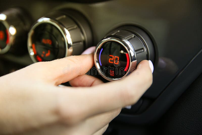 La mano humana ajusta el sistema de control del clima en el coche fotografía de archivo