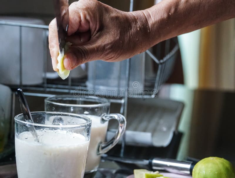 La mano maschio ha messo la calce in bevanda del latte di soia fotografie stock La mano maschio ha messo la calce in bevanda del latte di soia fotografie stock