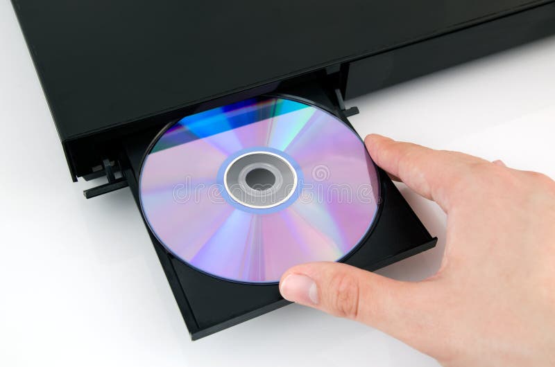 La mano mette il disco nel riproduttore di CD fotografia stock La mano mette il disco nel riproduttore di CD fotografia stock