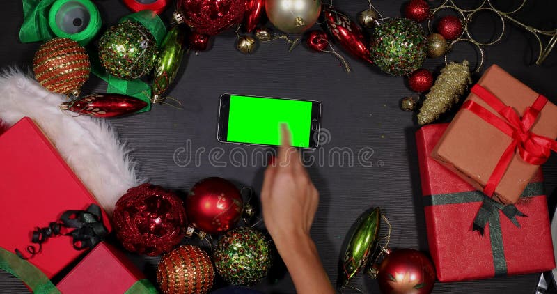 La mano utiliza smartphone entre los ornamentos de Navidad