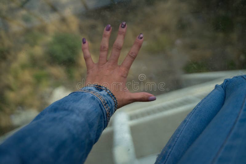 Hand and leg in jeans on glass and underneath a mountain. Hand and leg in jeans on glass and underneath a mountain