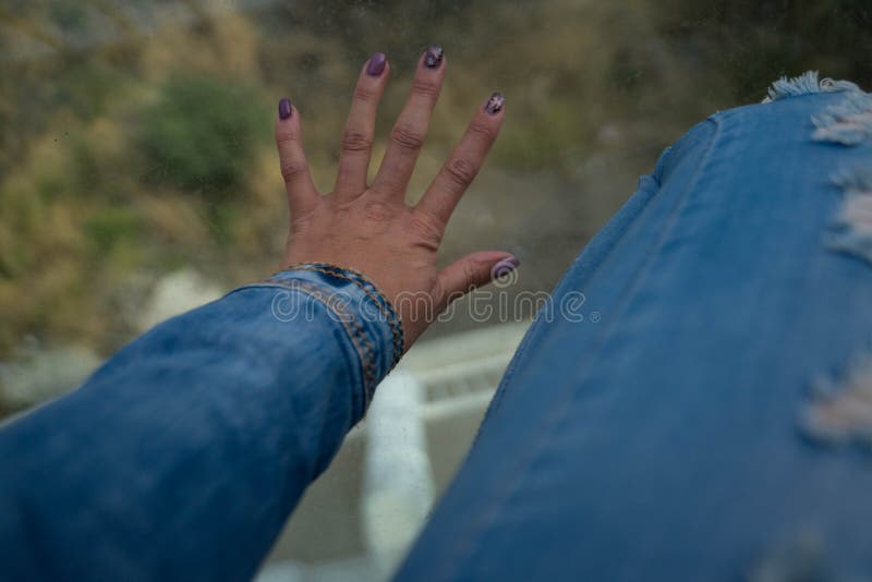 Hand and leg in jeans on glass and underneath a mountain. Hand and leg in jeans on glass and underneath a mountain