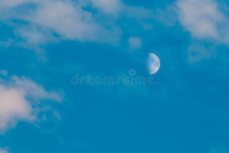 La mezza luna è veduta di giorno, in cielo blu con le nuvole esili fotografia stock libera da diritti La mezza luna è veduta di giorno, in cielo blu con le nuvole esili fotografia stock libera da diritti