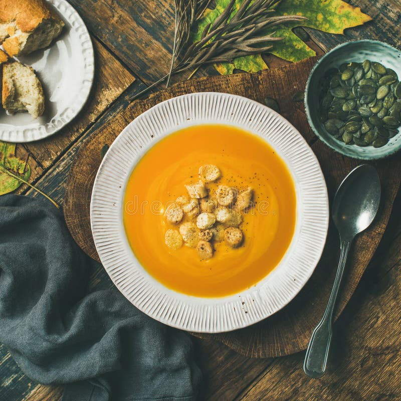 La minestra crema di riscaldamento della zucca con i crostini ed i semi, quadra il raccolto fotografia stock La minestra crema di riscaldamento della zucca con i crostini ed i semi, quadra il raccolto fotografia stock