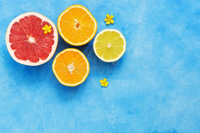 La mitad del pomelo, el limón y la naranja se adornan con las pequeñas flores amarillas en un fondo azul Visión desde arriba, esp foto de archivo libre de regalías La mitad del pomelo, el limón y la naranja se adornan con las pequeñas flores amarillas en un fondo azul Visión desde arriba, esp foto de archivo libre de regalías
