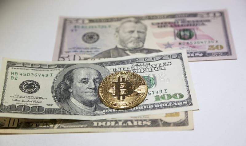 La moneta dorata del bitcoin sui dollari americani si chiude su fotografia stock La moneta dorata del bitcoin sui dollari americani si chiude su fotografia stock