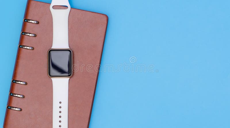 La montre intelligente sur le carnet pour organisent le concept sur le bleu photo libre de droits La montre intelligente sur le carnet pour organisent le concept sur le bleu photo libre de droits