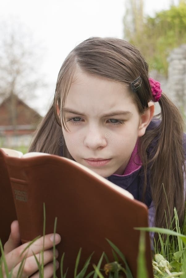 Teen girl reads book laying on grass. Teen girl reads book laying on grass