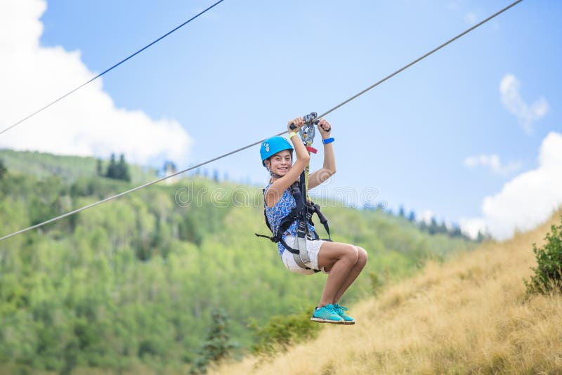 La muchacha adolescente sonriente que se divierte que monta un zipline monta foto de archivo libre de regalías La muchacha adolescente sonriente que se divierte que monta un zipline monta foto de archivo libre de regalías