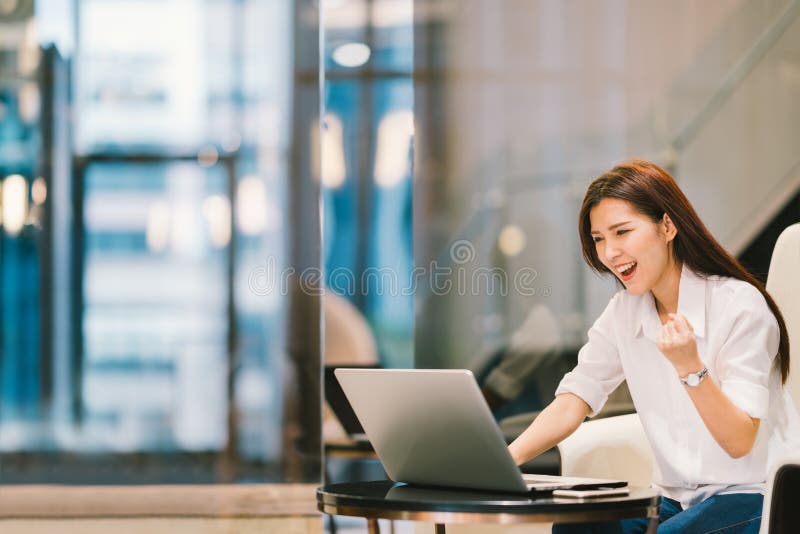 La muchacha asiática hermosa celebra con el ordenador portátil, actitud del éxito, educación o tecnología o concepto del negocio