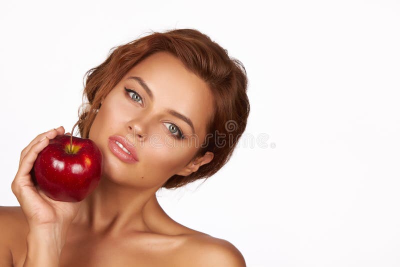 La muchacha atractiva hermosa joven con el pelo rizado oscuro, los hombros desnudos y el cuello, sosteniendo la manzana roja gran imagenes de archivo La muchacha atractiva hermosa joven con el pelo rizado oscuro, los hombros desnudos y el cuello, sosteniendo la manzana roja gran imagenes de archivo