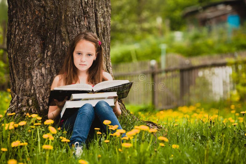 A girl 11 years old reads a book in the meadow. A girl 11 years old reads a book in the meadow.