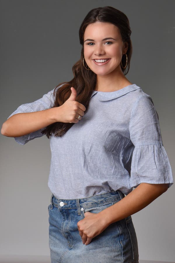 La muchacha bastante adolescente con sonrisa hermosa da los pulgares para arriba foto de archivo libre de regalías La muchacha bastante adolescente con sonrisa hermosa da los pulgares para arriba foto de archivo libre de regalías