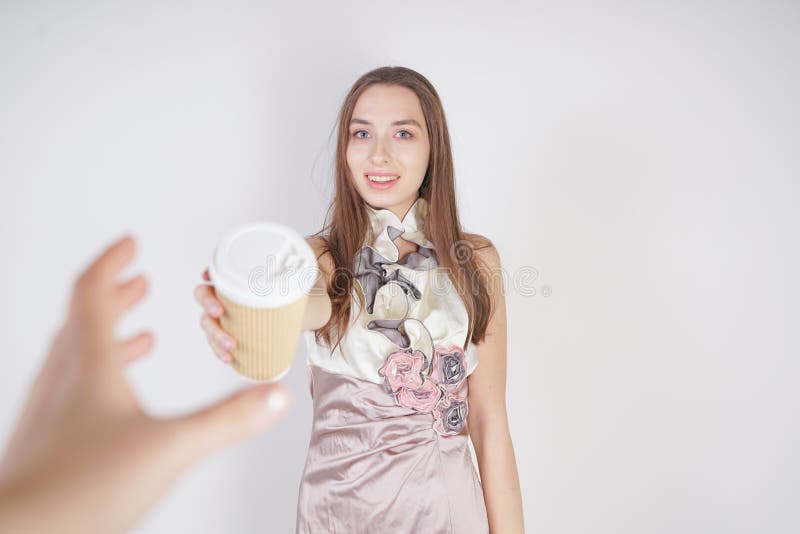La muchacha caucásica adolescente linda en un vestido de noche bonito da una taza de café de papel, tratando al interlocutor y fotografía de archivo La muchacha caucásica adolescente linda en un vestido de noche bonito da una taza de café de papel, tratando al interlocutor y fotografía de archivo