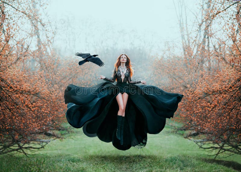 La muchacha con el pelo rojo brillante eleva y mantiene flotando sobre la tierra, bruja potente, diosa del bosque en vestido que imagen de archivo La muchacha con el pelo rojo brillante eleva y mantiene flotando sobre la tierra, bruja potente, diosa del bosque en vestido que imagen de archivo
