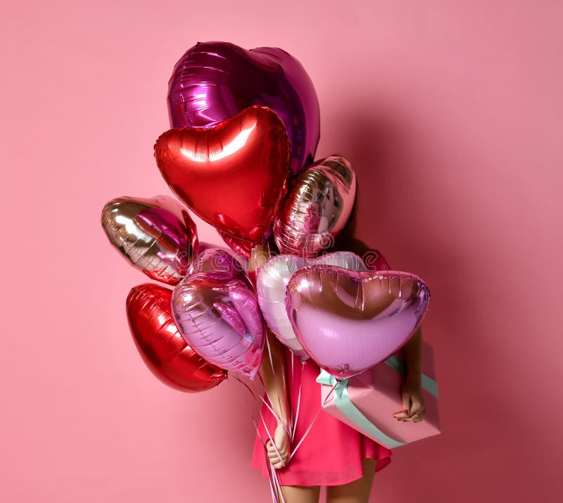La muchacha con los corazones coloridos aire los balones que ocultan detrás en la celebración de días festivos del cumpleaños que imágenes de archivo libres de regalías La muchacha con los corazones coloridos aire los balones que ocultan detrás en la celebración de días festivos del cumpleaños que imágenes de archivo libres de regalías