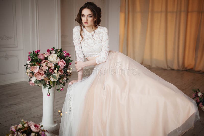 La muchacha con maquillaje en un vestido de boda se sienta en un cuarto hermoso fotos de archivo libres de regalías La muchacha con maquillaje en un vestido de boda se sienta en un cuarto hermoso fotos de archivo libres de regalías