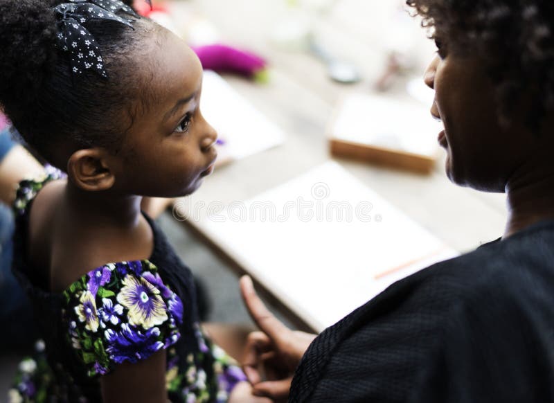 La muchacha de la ascendencia africana está escuchando su profesor