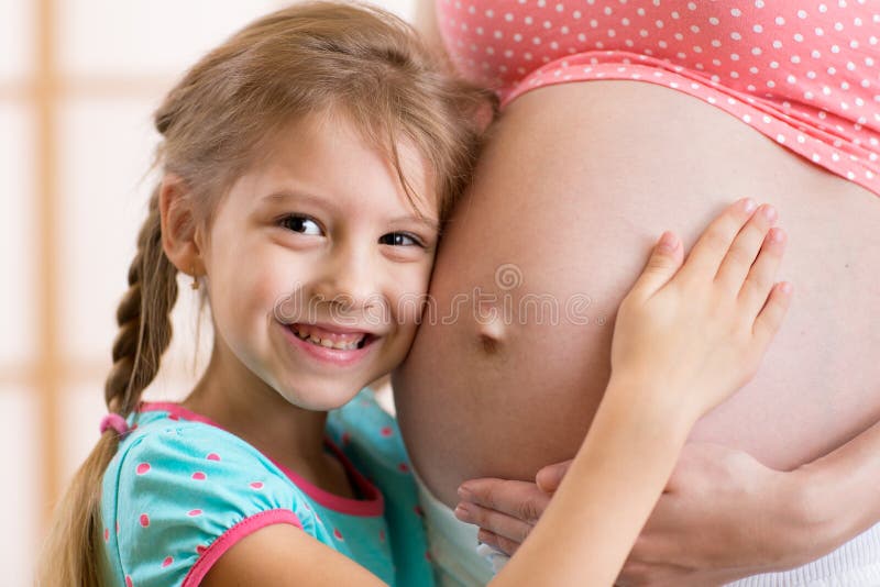 La muchacha del niño abraza el vientre de su madre embarazada foto de archivo libre de regalías La muchacha del niño abraza el vientre de su madre embarazada foto de archivo libre de regalías