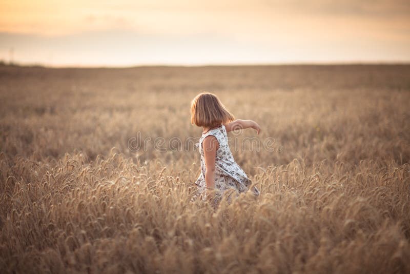 La muchacha divertida baila en campo con centeno en la puesta del sol imagen de archivo La muchacha divertida baila en campo con centeno en la puesta del sol imagen de archivo