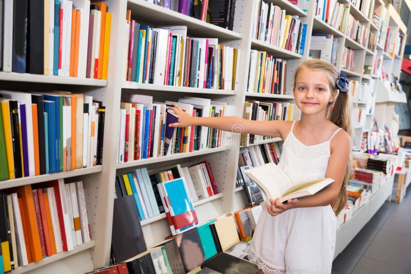 La muchacha elige un libro en la biblioteca foto de archivo libre de regalías La muchacha elige un libro en la biblioteca foto de archivo libre de regalías