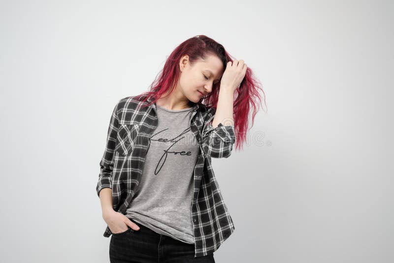 La muchacha en una camisa gris de la tela escocesa en un fondo blanco con el pelo rojo teñido fotografía de archivo libre de regalías La muchacha en una camisa gris de la tela escocesa en un fondo blanco con el pelo rojo teñido fotografía de archivo libre de regalías