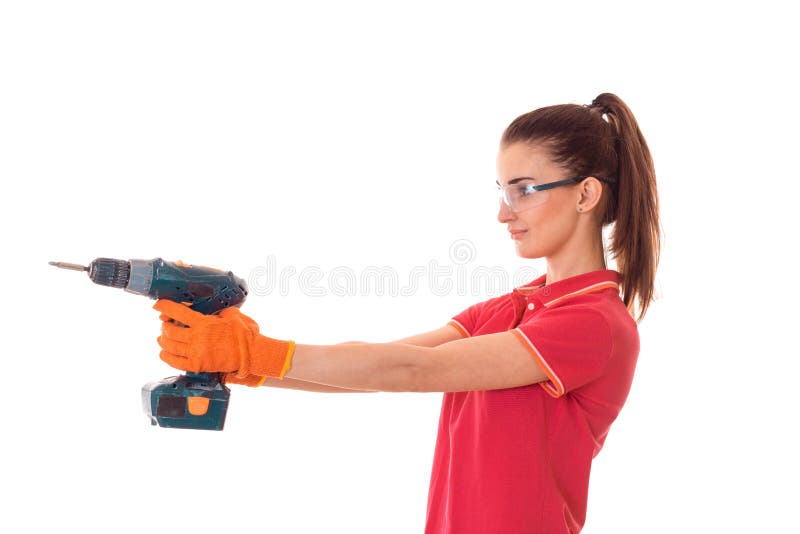La muchacha encantadora joven del constructor en uniforme con el taladro hace la renovación aislado en el fondo blanco fotos de archivo libres de regalías