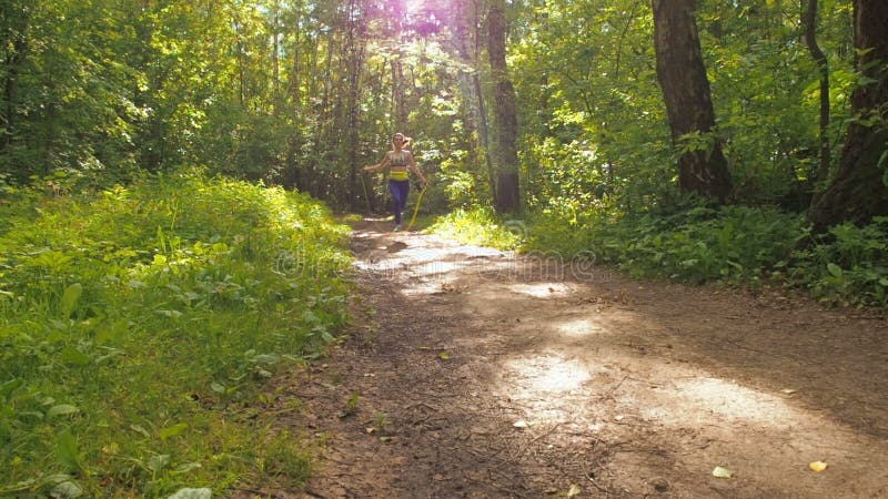 La muchacha es cuerda de salto en el parque Chica joven que hace deportes en el bosque