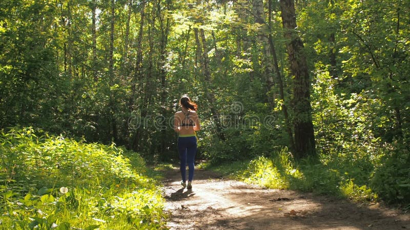 La muchacha es cuerda de salto en el parque Chica joven que hace deportes en el bosque