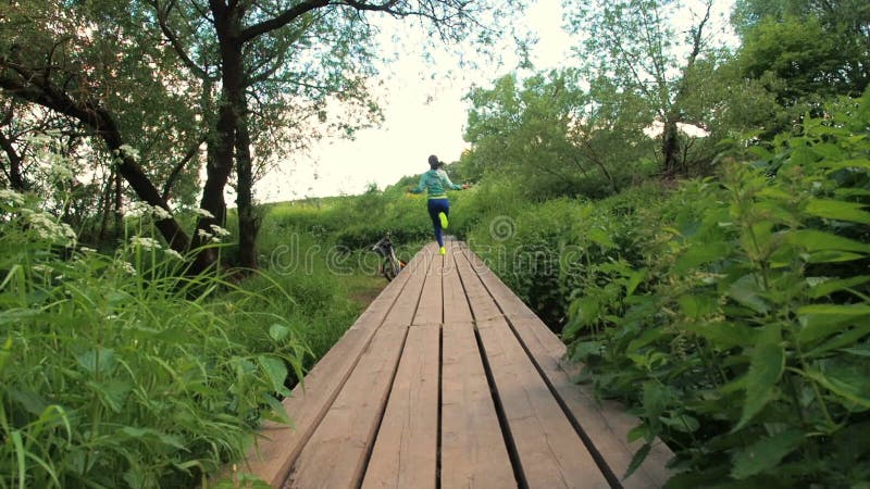 La muchacha es cuerda de salto en el parque Chica joven que hace deportes en el bosque