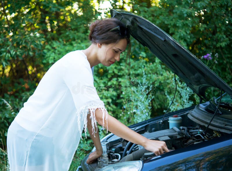 La muchacha está intentando reparar un coche quebrado fotos de archivo La muchacha está intentando reparar un coche quebrado fotos de archivo
