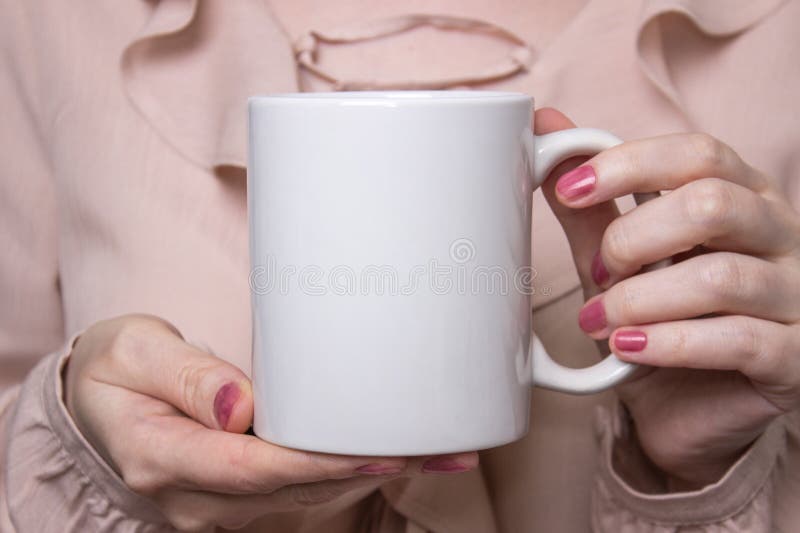 La muchacha está sosteniendo la taza blanca en manos Taza blanca para la mujer, regalo Maqueta para los diseños
