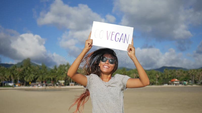 La muchacha feliz joven con va muestra de la propaganda de la dieta sana del vegano en una playa KOH Phangan, Tailandia HD a cáma