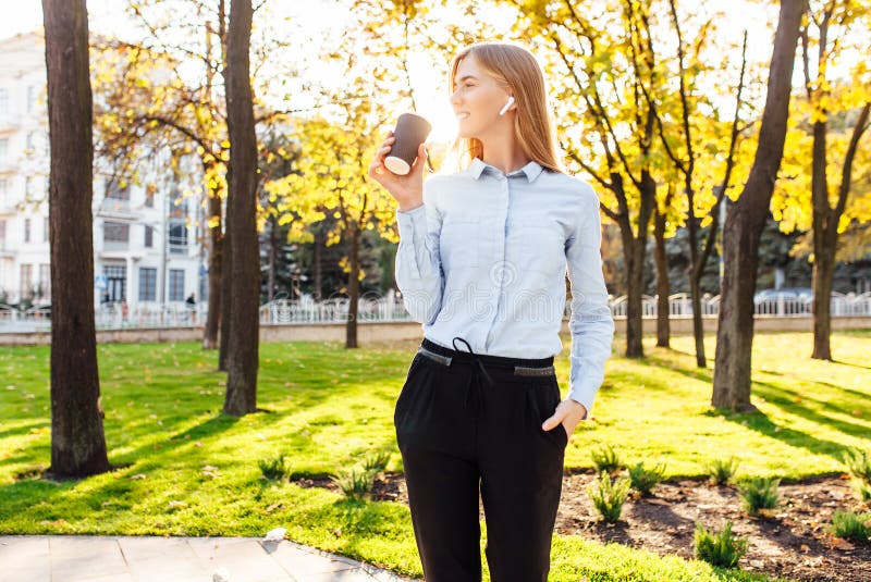 La muchacha hermosa joven, en ropa oficial, café de las bebidas, escucha imagen de archivo La muchacha hermosa joven, en ropa oficial, café de las bebidas, escucha imagen de archivo