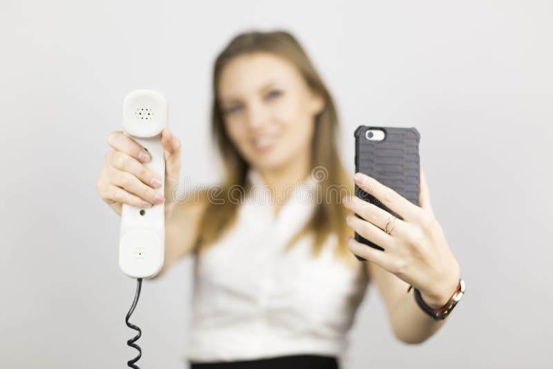 La muchacha hermosa sostiene dos teléfonos foto de archivo