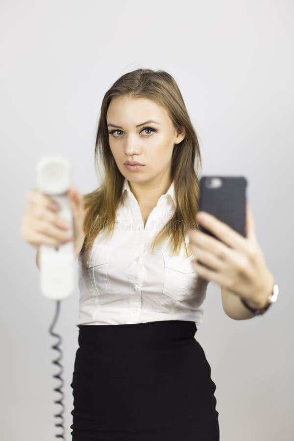La muchacha hermosa sostiene dos teléfonos foto de archivo