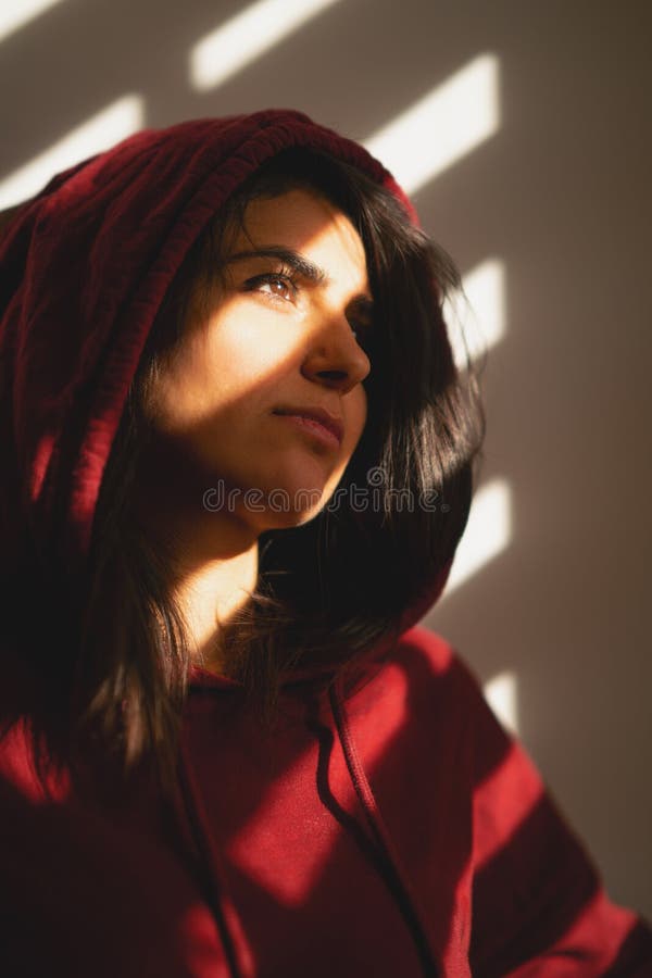 La muchacha infeliz se coloca sola en las persianas de ventana fotografía de archivo La muchacha infeliz se coloca sola en las persianas de ventana fotografía de archivo
