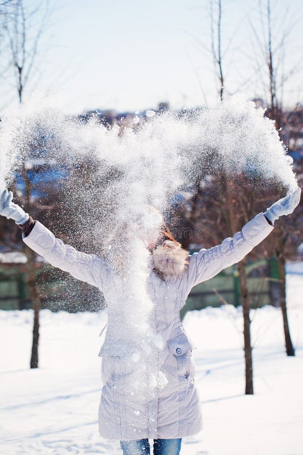 La muchacha lanza nieve por la tarde escarchada del invierno imágenes de archivo libres de regalías La muchacha lanza nieve por la tarde escarchada del invierno imágenes de archivo libres de regalías