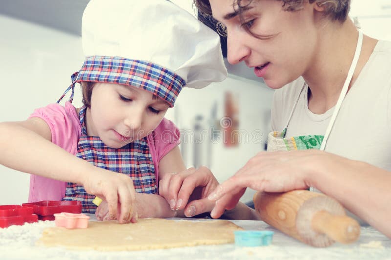 La muchacha linda con su madre cuece las galletas en casa foto de archivo La muchacha linda con su madre cuece las galletas en casa foto de archivo