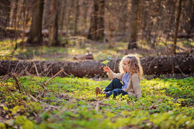 La muchacha linda del niño que se sienta en verde se va en bosque temprano de la primavera imagen de archivo libre de regalías La muchacha linda del niño que se sienta en verde se va en bosque temprano de la primavera imagen de archivo libre de regalías