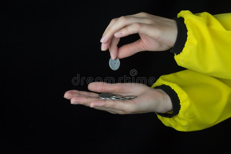 La muchacha pone la moneda a disposición, primer, fondo negro, amarillo fotografía de archivo libre de regalías La muchacha pone la moneda a disposición, primer, fondo negro, amarillo fotografía de archivo libre de regalías