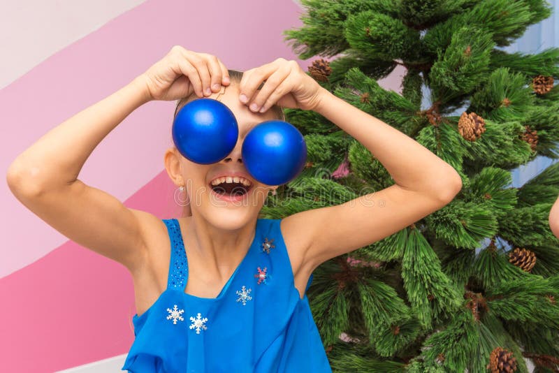 La muchacha puso bolas grandes de la Navidad a sus ojos foto de archivo libre de regalías La muchacha puso bolas grandes de la Navidad a sus ojos foto de archivo libre de regalías