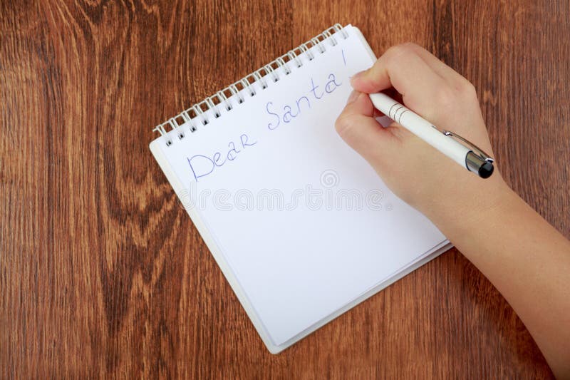 La muchacha que escribe una letra a Santa Claus en la tabla de madera fotografía de archivo libre de regalías La muchacha que escribe una letra a Santa Claus en la tabla de madera fotografía de archivo libre de regalías
