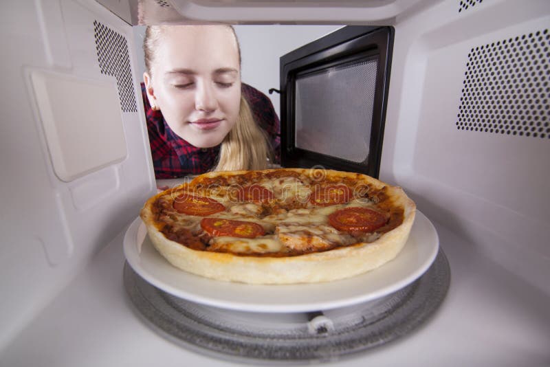 La muchacha que la cerraba los ojos que olían el aroma de la pizza cocinó en microonda