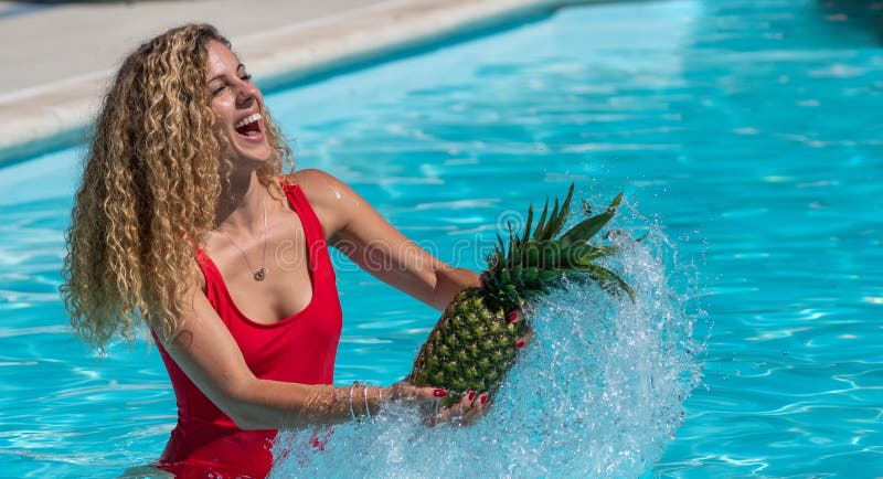La muchacha rubia caucásica juega con una piña en la piscina fotografía de archivo libre de regalías La muchacha rubia caucásica juega con una piña en la piscina fotografía de archivo libre de regalías